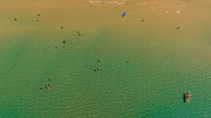 Aerial view of people bathing in the crystal-clear emerald sea. Vacation concept and background.