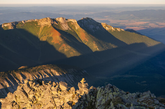 Aerial view of the majestic Jahnaci stit peak is bathed in golden light, its craggy slopes casting dramatic shadows across the landscape, Vysoke Tatry, Presov Region, Slovakia.