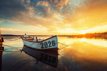 2026 concept Fishing Boat on Varna lake with a reflection in the water at sunset.