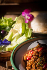 A plate of traditional Southern Thai Khua Kling stir-fried minced pork served in a rustic bowl, topped with red chili and sliced kaffir lime leaves. 