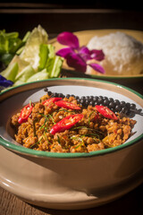 A plate of traditional Southern Thai Khua Kling stir-fried minced pork served in a rustic bowl, topped with red chili and sliced kaffir lime leaves. 