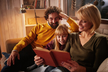 In a warm, inviting living room, a family sits together on a couch, enjoying a book. The atmosphere is cozy as they share laughter and moments of joy, creating lasting memories.