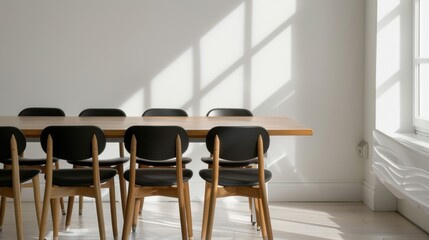 A modern conference room with a long wooden table and black chairs. Bright sunlight casts shadows on the white walls, creating a clean and minimalistic atmosphere.