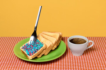 Toast stack with sprinkles and fork beside cup of coffee on checked tablecloth. Concept of cafe...