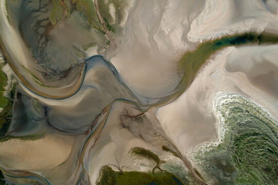 Aerial view of swirling sands and meandering streams converge in a ballet of earthy tones, where the tide's ebb and flow sculpts a mesmerizing coastal tableau, Dornoch, United Kingdom.
