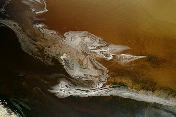 Aerial view of swirling patterns of white foam dance across the dark, coffee-colored water, creating a mesmerizing display of nature's artistry, Dornoch, United Kingdom.