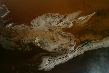 Aerial view of swirling patterns of white and brown merge in a beautiful dance across the water's surface, like an abstract painting, Dornoch, United Kingdom.