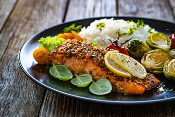 Baked salmon with white rice and Brussels sprouts on wooden table	