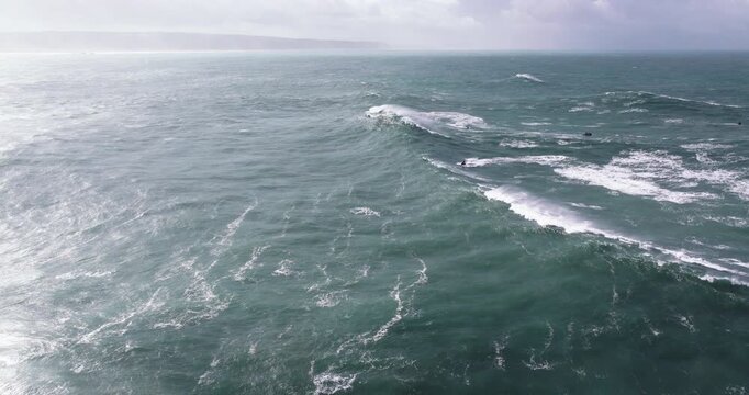 Aerial drone shot of big wave surfer surfing a wave on a day with giant waves in Nazare, Portugal, Europe. Nazaré, big wave surfing town with biggest waves in the world. Professional surfing