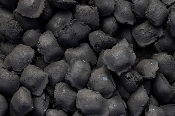 charcoal compressed from crumbs is obtained under pressure and used to light a fire and cook food on the grill, black charcoal in briquettes for barbecues