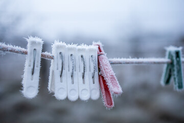 The clothespins are frozen from the cold, hanging in the yard. Hoarfrost. Clothespin covered in...
