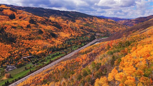 Vail Village Vail mountain ski resort ski trails morning aerial drone fall autumn vibrant colorful quaking aspen trees October blue sky clouds White River National Forest i70 highway cars forward pan