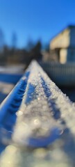 Macro close-up of sparkling frost and ice crystals on a blue railing. Frozen texture in bright winter sunlight with a blurred background