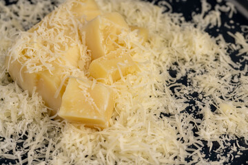 finely grated fresh hard cheese on a grater for pizza or pasta, yellow grated cheese with pieces for cooking various foods