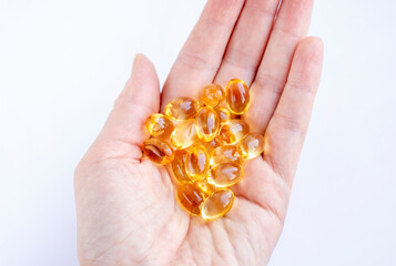 Fototapeta premium Omega 3 capsules, vitamin D, vitamin E, fish oil capsules in hand on a white background. Biologically active food supplement. Proper healthy eating.