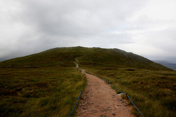 Summit of Ben Nevis in Scotland with misty clouds rolling over the rocky peak, capturing dramatic mountain atmosphere and shifting highland weather.