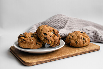 Fresh cookies with raisins and nuts on white plate. Homemade baked goods on light background.