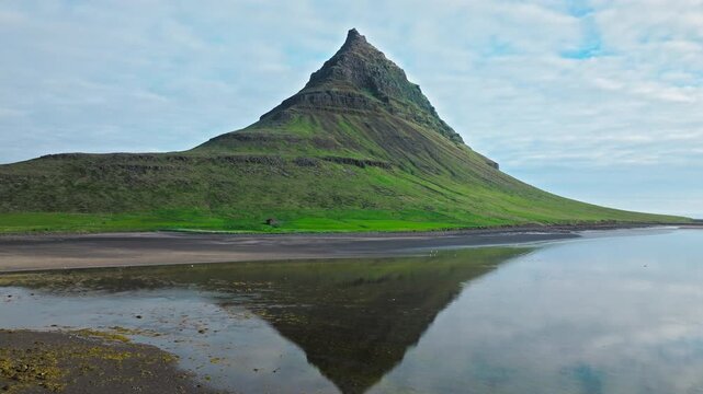 Aerial view of Kirkjufell, Iceland. Perfect reflection in still fjord water under blue sky.