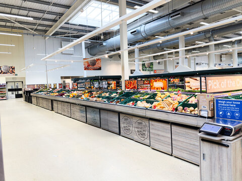 Customer shopping in a modern Manchester supermarket produce aisle, exploring fresh fruits and vegetables