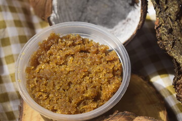 Detalhe de cocada caseira em pote de plástico transparente ao lado de coco seco ralado, receita rústica