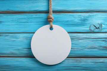 Blank round gift tag hanging on blue wooden background