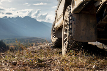 Close up photo of car wheel. 4x4 offroad ready car is standing at view point against mountain valley