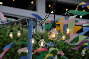 String lights featuring vintage Edison bulbs and colorful bunting decorations hanging outdoors for a festive event or party