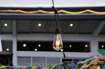 String lights featuring vintage Edison bulbs and colorful bunting decorations hanging outdoors for a festive event or party