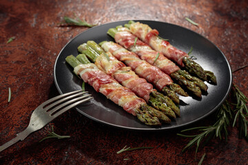 Grilled green asparagus with bacon on a brown vintage background.