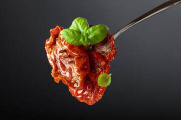 Sun dried tomatoes in olive oil with green basil.