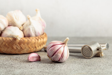 Garlic and garlic press on a kitchen table.