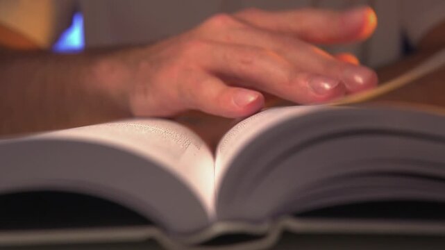 cinematic close-up of a student or professional hand quickly flipping book pages during intense reading or research session at night