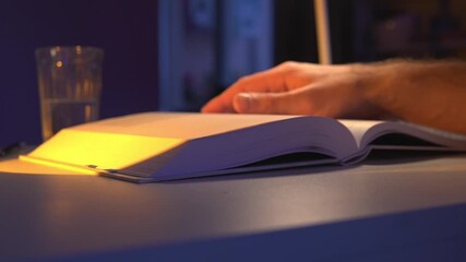 cinematic close-up of a student or professional hand quickly flipping book pages during intense reading or research session at night - Powered by Adobe