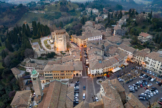 Aerial view of ancient buildings clustered together with Rocca, Cathedral, and parking area, nestled among green hills, Asolo, Veneto, Italy.