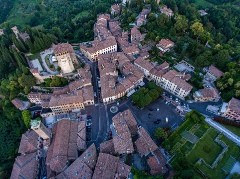Aerial view of terracotta rooftops nestled in verdant hillsides, ancient structures casting shadows in the fading light, Piazza Garibaldi a focal point, Asolo, Veneto, Italy.