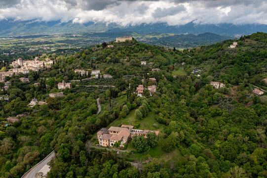 Aerial view of the Rocca d'Asolo castle atop a lush green hill, a serene contrast to the scattered buildings below, Asolo, Veneto, Italy.