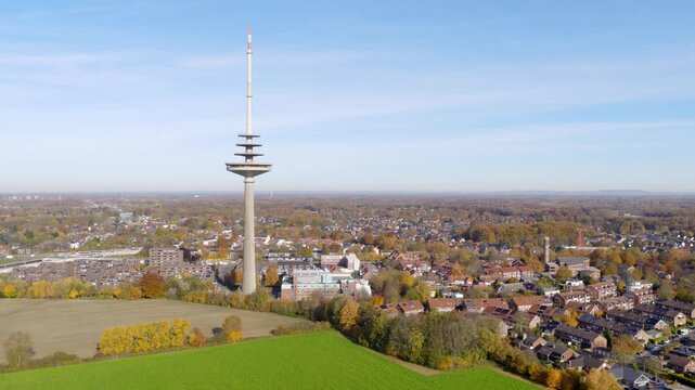 The M&uuml;nster telecommunication tower rises above the autumn cityscape, with the Dortmund-Ems Canal, ships and wide forest areas in the background.

