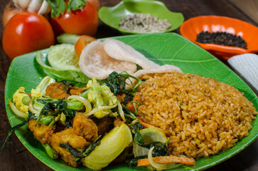 Indonesian Fried Rice with Egg and Crackers Served on Green Plate – Nasi Goreng Traditional Dish with Fresh Vegetables and Spices
