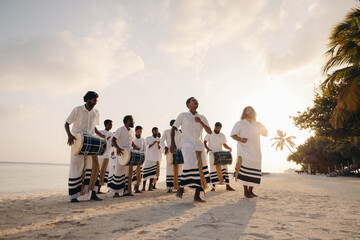 Maldivian cultural drumming performance on sandy beach at sunset