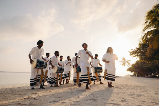 Maldivian cultural drumming performance on sandy beach at sunset