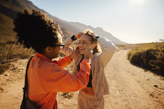 Friends sharing sunscreen on sunny trail