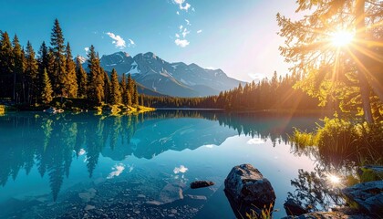 A serene mountain lake with clear turquoise water reflects evergreen trees and majestic snow-capped mountains under a bright, sun-drenched sky.