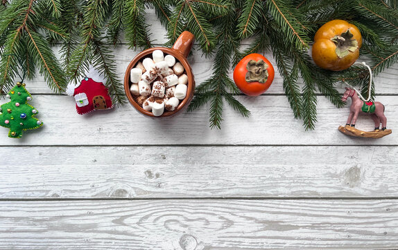 Background for New Year's greetings. Natural fir branches, felt Christmas tree toys, horse toys, persimmons. A cup of marshmallows. - Powered by Adobe