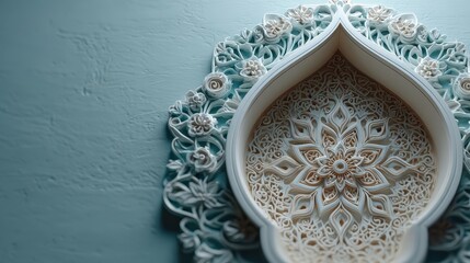 Close up of an ornate white Islamic architectural element featuring detailed floral carvings set against a textured light blue wall.