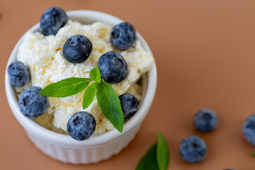 A bowl of cottage cheese decorated with blueberries and aromatic mint leaves