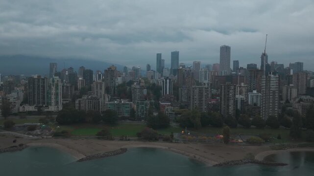 Wide dolly aerial shot of public beaches at English Bay in downtown Vancouver on a rainy day in British Columbia, Canada. 4K