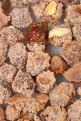 A close-up, full-frame view captures a pile of hazelnuts coated in a grainy, sugary crust, creating a dense, sweet texture