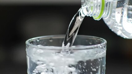 Fresh drinking water poured from plastic bottle into a glass for refreshment - Powered by Adobe
