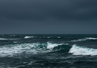 Dramatic ocean waves crash under an overcast sky, showcasing the raw, untamed power of nature. A vast, deep blue-grey expanse ,wild ,horizon ,immense