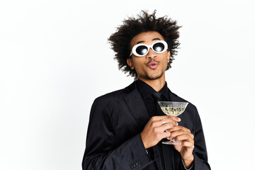 Stylishly posing young man enjoys a cocktail while dressed to impress in elegant attire